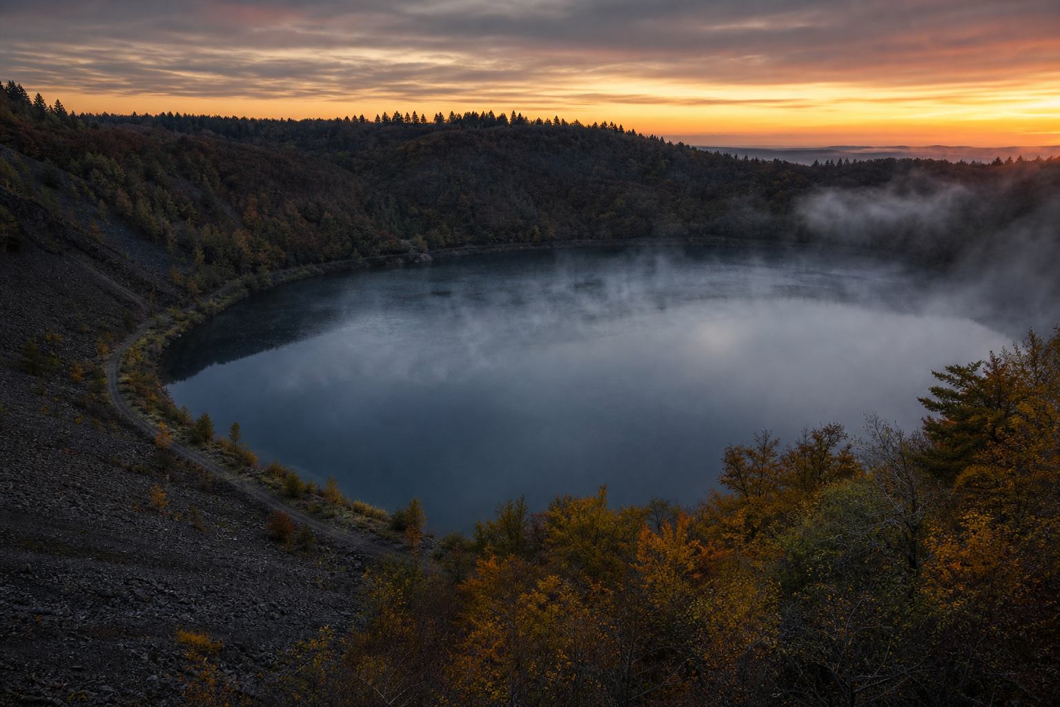 Frühmorgendlicher Kratersee in der Vulkaneifel mit Nebel über dem Wasser
